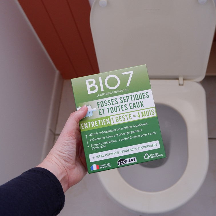 photo du produit BIO 7 pour l'entretien pour résidences secondaires en 1 seul geste des fosses septiques et fosses toutes eaux, tenu au dessus d'une cuvette de toilettes propres